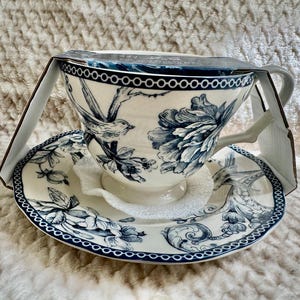 K&ouml;nnte beinhalten: Wei&szlig;es Tee-Set mit blauem Blumen- und Vogelmuster. Die Tasse hat einen Henkel und steht auf einer passenden Untertasse. Das Set ist neu in der Originalverpackung.