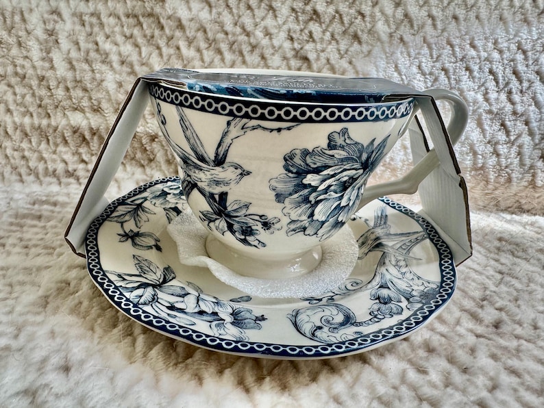 K&ouml;nnte beinhalten: Wei&szlig;es Tee-Set mit blauem Blumen- und Vogelmuster. Die Tasse hat einen Henkel und steht auf einer passenden Untertasse. Das Set ist neu in der Originalverpackung.