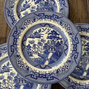 K&ouml;nnte beinhalten: Vier blaue und wei&szlig;e Keramik-Dinnerteller mit einem traditionellen Weidenmuster. Die Teller haben einen wei&szlig;en Hintergrund mit einem blauen Weidenbaumdesign und einem blauen Rand.