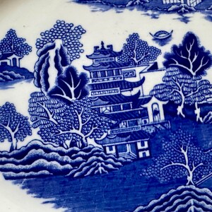 K&ouml;nnte beinhalten: Blau-wei&szlig;e Porzellanplatte mit einem traditionellen chinesischen Landschaftsdesign. Das Design zeigt eine Pagode, B&auml;ume und einen Fluss.