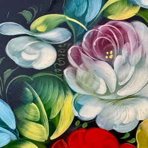 May include: Close-up of a floral painting featuring white, pink, red, yellow, and blue flowers with green leaves against a dark background. The flowers are painted with detailed brushstrokes, showcasing a vibrant and colorful design.