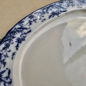 Puede incluir: Un plato de cer&aacute;mica blanca con un borde floral azul. El plato tiene un borde ligeramente curvado y un acabado brillante. El dise&ntilde;o floral azul es intrincado y detallado, agregando un toque de elegancia a la vajilla.