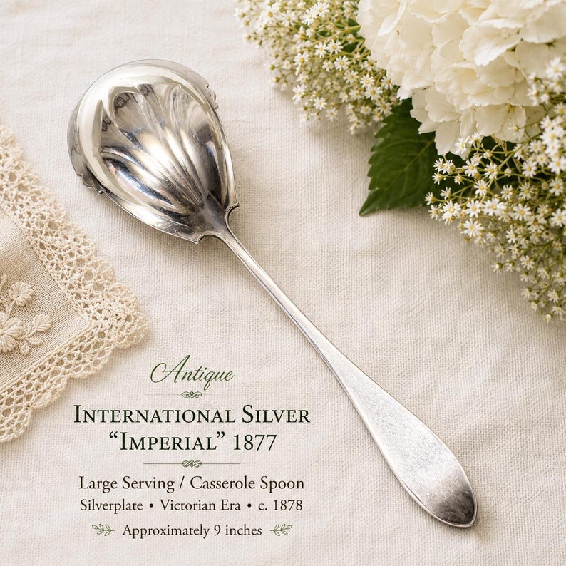 May include: A silver-plated serving or casserole spoon with a shell-patterned bowl. The text reads: Antique International Silver "IMPERIAL" 1877, Large Serving / Casserole Spoon, Silverplate, Victorian Era, c. 1878, Approximately 9 inches.