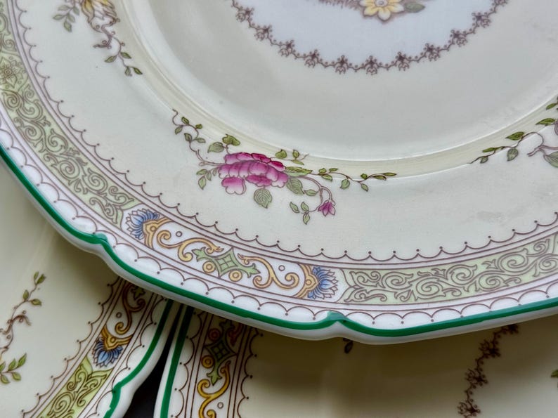 Puede incluir: Un juego de tres platos de cer&aacute;mica blanca con un patr&oacute;n floral verde y dorado. Los platos tienen un borde festoneado y un borde verde.
