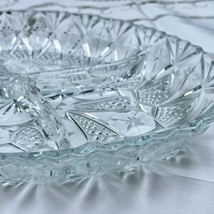 May include: Clear glass serving dish with three compartments. The dish has a diamond and starburst pattern. The rim has a scalloped edge. The dish is designed for serving appetizers or snacks.