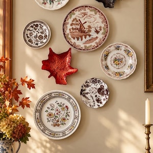 May include: A wall display featuring seven decorative plates and two leaf-shaped wall plaques. The collection includes floral patterns, a windmill landscape, and dark botanical designs in red, brown, white, and black colors.