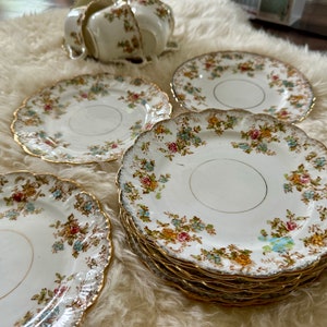 K&ouml;nnte beinhalten: Set aus vintage floral gemusterten Teetassen und Untertassen mit goldenen Verzierungen. Die Tassen und Untertassen sind wei&szlig; mit einem zarten Blumenmuster in Rosa-, Blau- und Gelbt&ouml;nen. Die goldene Verzierung verleiht dem Set einen Hauch von Eleganz.