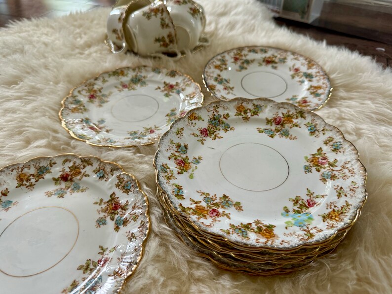 K&ouml;nnte beinhalten: Set aus vintage floral gemusterten Teetassen und Untertassen mit goldenen Verzierungen. Die Tassen und Untertassen sind wei&szlig; mit einem zarten Blumenmuster in Rosa-, Blau- und Gelbt&ouml;nen. Die goldene Verzierung verleiht dem Set einen Hauch von Eleganz.
