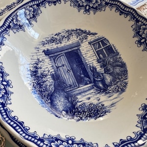 K&ouml;nnte beinhalten: Eine blaue und wei&szlig;e Keramiksch&uuml;ssel mit einem Cottage- und Kaninchen-Design. Die Sch&uuml;ssel hat einen gewellten Rand und ein blaues Blumenmuster.