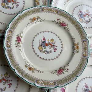 Puede incluir: Juego de cuatro platos de cena de porcelana blanca vintage con un patr&oacute;n floral verde y dorado. Los platos tienen un borde festoneado y un delicado dise&ntilde;o floral.