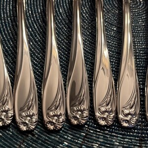 May include: Set of eight silver-plated dinner forks with ornate floral designs. The forks have a polished finish and are arranged in a row.