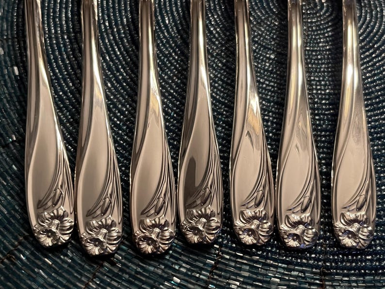 May include: Set of eight silver-plated dinner forks with ornate floral designs. The forks have a polished finish and are arranged in a row.
