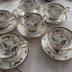 May include: Set of six teacups and saucers with a black and white floral pattern and gold trim. The cups and saucers are made of fine china.