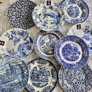 Pode incluir: Uma coleção de dez pratos redondos de cerâmica com vários padrões em azul e branco, incluindo motivos florais, paisagens rurais, um design de pavão e cenas tradicionais, cada um marcado com uma pequena etiqueta Royal Stafford.