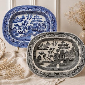 May include: Two oval ceramic platters featuring a detailed willow pattern. One platter displays a blue and white color scheme, while the other features a black and white design. Both platters show a landscape with a bridge, trees, and buildings.