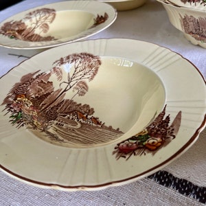 May include: A set of four vintage cream-coloured soup bowls with a brown and green woodland scene design. The bowls have a scalloped edge and a raised rim.