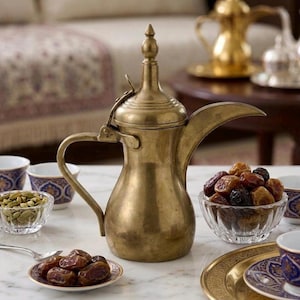Peut inclure: Une cafetière traditionnelle dorée avec un long bec et une poignée incurvée. Autour, de petits bols de dattes, de noix et des tasses à motifs suggèrent une réunion ou un repas culturel.