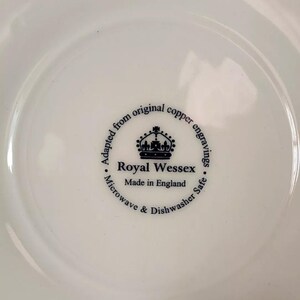 K&ouml;nnte beinhalten: Nahaufnahme der Unterseite eines wei&szlig;en Keramiktellers mit einem schwarz-wei&szlig;en Logo, auf dem steht "Adapted from original copper engravings. Royal Wessex. Made in England. Microwave & Dishwasher Safe."