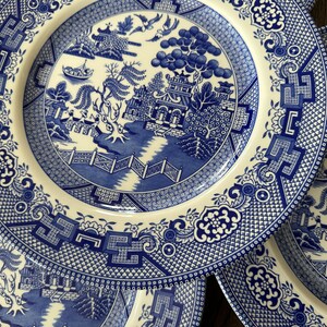 K&ouml;nnte beinhalten: Drei blaue und wei&szlig;e Keramikteller mit einem traditionellen Weidenmuster. Die Teller zeigen ein detailliertes Design eines Weidenbaums, einer Br&uuml;cke und einer Pagode.