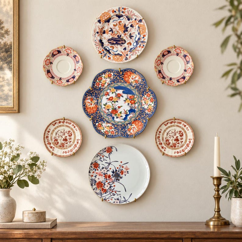 Pu&ograve; includere: Una collezione di sette piatti decorativi in ceramica montati su una parete in una disposizione simmetrica. I piatti presentano intricati motivi floreali e botanici nei toni del blu, rosso, arancione e bianco, con bordi vari e smerlati.