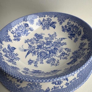 K&ouml;nnte beinhalten: Eine gro&szlig;e, wei&szlig;e Keramiksch&uuml;ssel mit einem blauen und wei&szlig;en Blumenmuster. Die Sch&uuml;ssel hat einen gewellten Rand und einen erh&ouml;hten Rand.