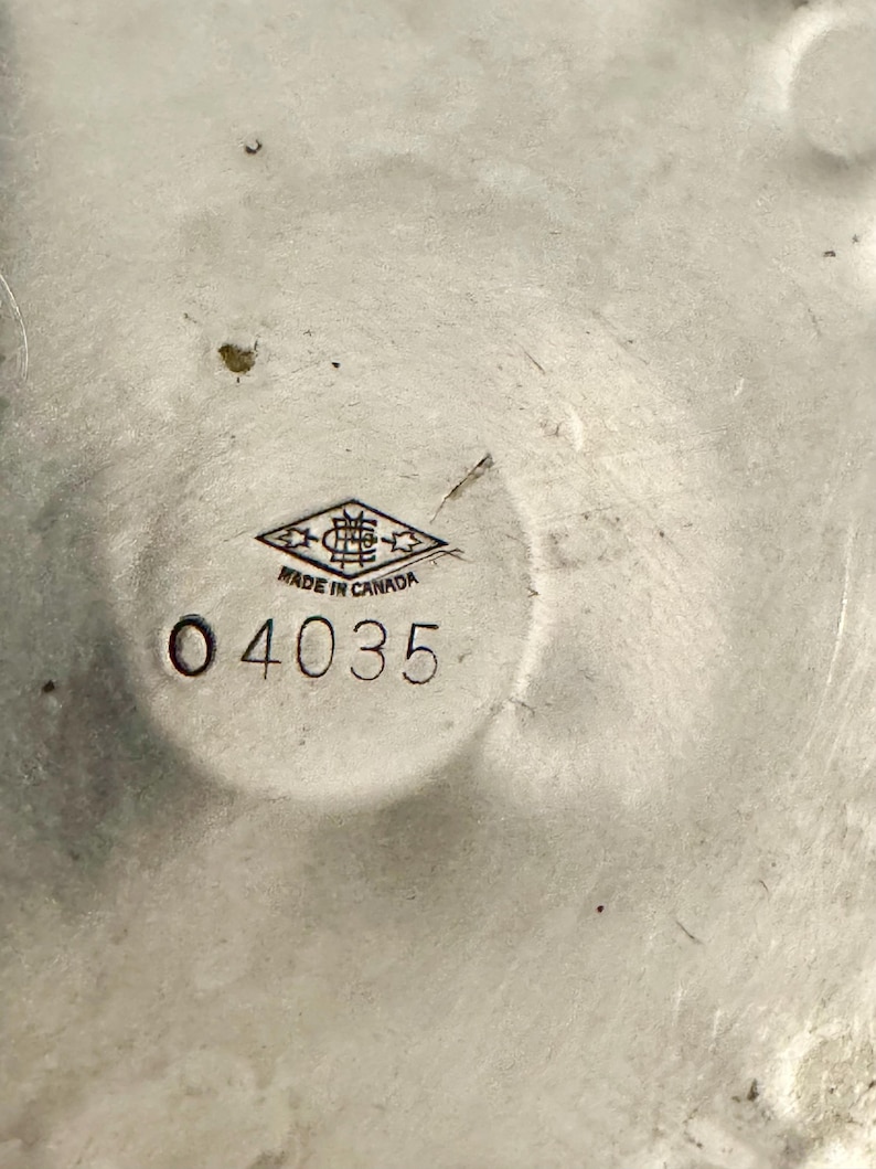 Peut inclure: Gros plan sur un objet m&eacute;tallique argent&eacute; avec un motif circulaire. Le texte "MADE IN CANADA" est visible, ainsi que le num&eacute;ro "04035". L'objet a une surface textur&eacute;e et semble &ecirc;tre vintage.