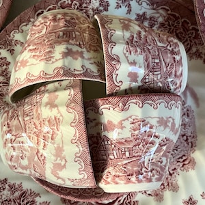 May include: Four vintage teacups with a pink and white floral pattern. The cups are stacked on top of each other and are arranged in a circle. The cups are made of porcelain and have a delicate design.