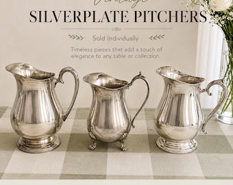 May include: Three silverplate pitchers with curved handles and pouring spouts. The text reads: Vintage SILVERPLATE PITCHERS, Sold Individually, Timeless pieces that add a touch of elegance to any table or collection, QUALITY SILVERPLATE, BEAUTIFUL VINTAGE CONDITION, PERFECT FOR DECOR OR USE, TIMELESS VINTAGE CHARM.