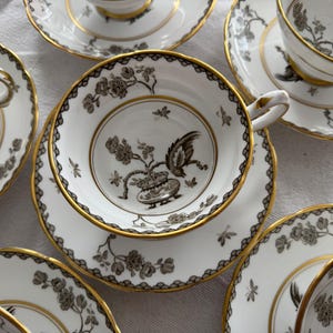 May include: A set of six teacups and saucers with a black and gold floral design. The cups and saucers are made of fine china and have a delicate, elegant look.