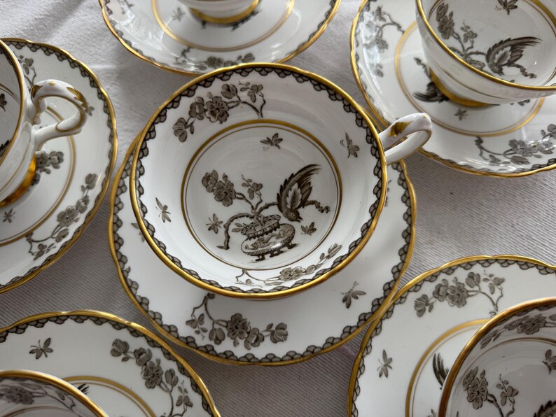 May include: A set of six teacups and saucers with a black and gold floral design. The cups and saucers are made of fine china and have a delicate, elegant look.