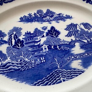 K&ouml;nnte beinhalten: Blau-wei&szlig;e ovale Servierplatte aus Porzellan mit traditionellem chinesischem Landschaftsdesign. Das Design zeigt eine Pagode, B&auml;ume, eine Br&uuml;cke und Wasser.