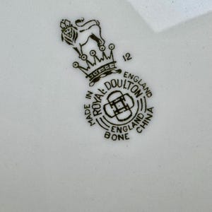 Puede incluir: Sello en blanco y negro con el texto "Made in England Royal Doulton Bone China" y un le&oacute;n con una corona encima. El n&uacute;mero "12" est&aacute; impreso a la derecha de la corona.