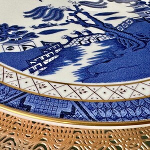 May include: A blue and white ceramic plate with a traditional Chinese design. The plate features a gold rim and a delicate floral pattern.