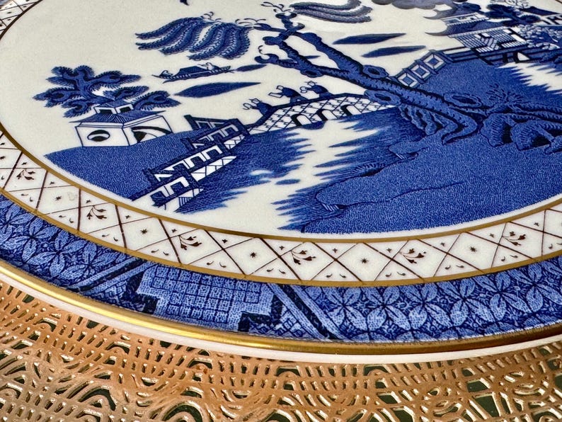 May include: A blue and white ceramic plate with a traditional Chinese design. The plate features a gold rim and a delicate floral pattern.