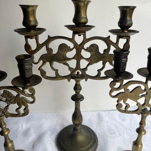 Pu&ograve; includere: Portacandele antichi in ottone con intricati disegni di leoni. Ogni portacandele presenta pi&ugrave; coppe per candele e bracci decorativi. La finitura in ottone anticato conferisce loro un aspetto vintage, perfetto per aggiungere eleganza.