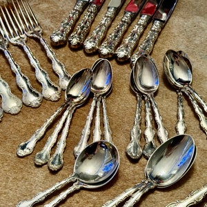 May include: A set of ornate silver flatware, including forks and spoons, with intricate designs and a polished finish.