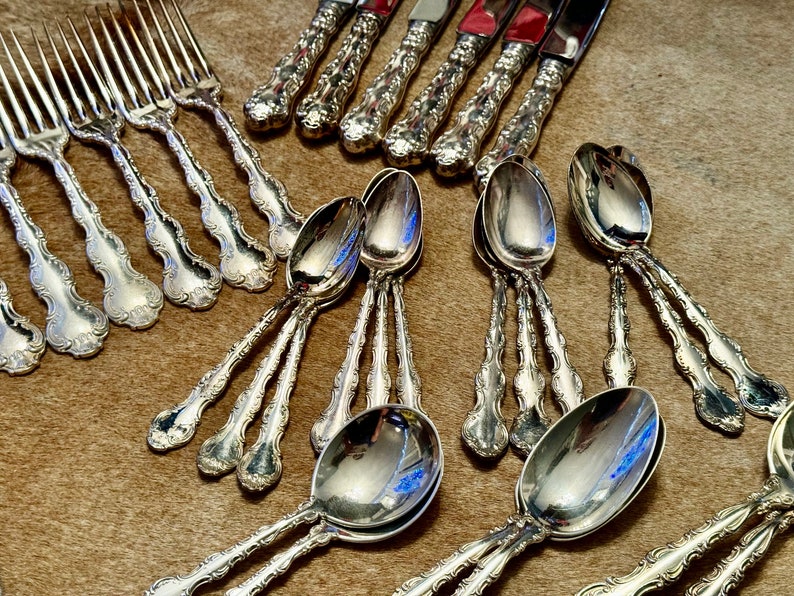 May include: A set of ornate silver flatware, including forks and spoons, with intricate designs and a polished finish.
