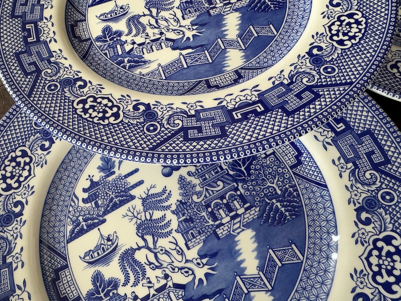 K&ouml;nnte beinhalten: Zwei blaue und wei&szlig;e Keramikteller mit einem traditionellen Weidenmuster. Die Teller sind &uuml;bereinander gestapelt.