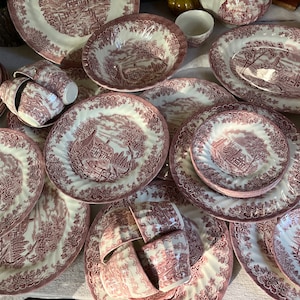 May include: A set of vintage pink and white china dinnerware with a floral pattern. The set includes plates, bowls, and cups.