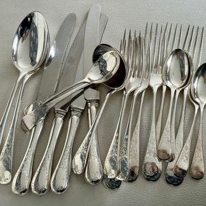 May include: An assortment of antique silverware, including spoons, forks, and knives. The silverware is made of a shiny, reflective metal, with ornate floral patterns on the handles. The spoons and forks have a rounded bowl and tines, respectively. The knives have a pointed blade.