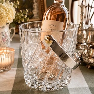 May include: A clear, faceted glass ice bucket with a polished silver-tone metal handle, containing a bottle of C&ocirc;tes de Provence ros&eacute; wine nestled among clear ice cubes. The bucket features a distinct spiral pattern etched into the glass.
