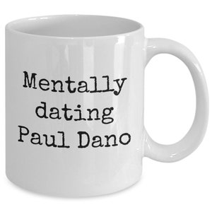 May include: White ceramic coffee mug with black text that reads "Mentally dating Paul Dano".