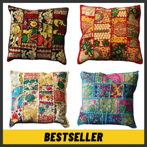 May include: Four square patchwork throw cushions in various colours, including red, black, gold, blue, and cream. The cushions have embroidered and textured details. The word "BESTSELLER" is displayed on a yellow banner. Each cushion has a unique design.