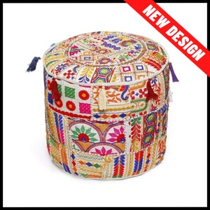 May include: Round, patchwork pouf with a vibrant mix of colors including red, yellow, blue, and green. The top features intricate embroidery and a tassel detail. The words "NEW DESIGN" are displayed on a red banner.