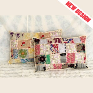 May include: Two rectangular patchwork pillows with a variety of colorful fabric squares. The pillows have a cream-colored border and are placed on a white and cream striped surface. The top right corner of the image has the text "NEW DESIGN" in red.