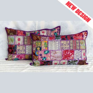 Peut inclure: Deux coussins rectangulaires en patchwork avec une bordure violette. Les coussins sont composés de divers carrés de tissu dans les tons de rose, violet, vert et marron. Les coussins sont sur une surface blanche. Le texte "NEW DESIGN" est dans le coin supérieur droit.