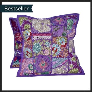 Puede incluir: Dos cojines decorativos cuadrados morados con un diseño de patchwork. Los cojines presentan patrones florales bordados en tonos de rosa, azul y verde. Los cojines tienen un borde morado y la palabra "Bestseller" está en la esquina superior izquierda.
