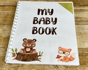 May include: A white baby book with a brown title "My Baby Book" and illustrations of a brown bear sitting on a tree stump and a fox wearing glasses.