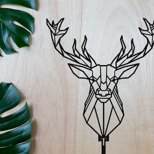 Puede incluir: Decoración de pared de cabeza de ciervo geométrico negro con un diseño minimalista. La cabeza de ciervo está hecha de metal y tiene un aspecto simple y moderno.