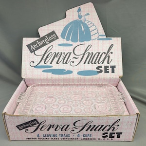 Könnte beinhalten: Ein Vintage-Set "Serva Snack" aus Anchor Hocking Glas in einer rosa und blauen Box. Das Set enthält vier Serviertabletts und vier Tassen. Die Box zeigt eine Cartoon-Illustration einer Frau in einem blauen Kleid.